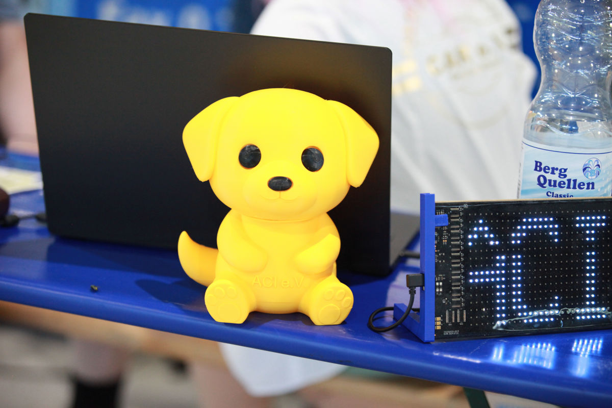 ACI-Spendendose und digitale Laufschrift bei der Rassehundeausstellung 2026 ACI-Spendendose in Hundeform neben der digitalen ACI-Laufschriftentafel auf der Internationalen Tandem-Rassehunde-Ausstellung 2026.